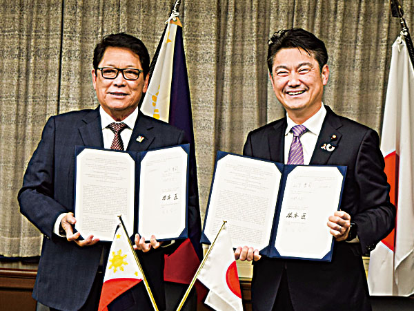 新たな在留資格「特定技能」の開始に合わせ協力覚書を交わす日本の山下貴司法相(右)とフィリピンのベリヨ労働雇用相=19年3月、東京(NNA撮影)